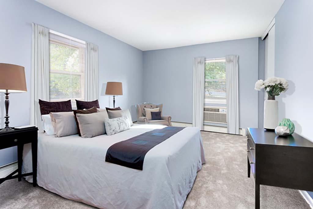 A bedroom with a bed and open windows at Bromley House apartments for rent